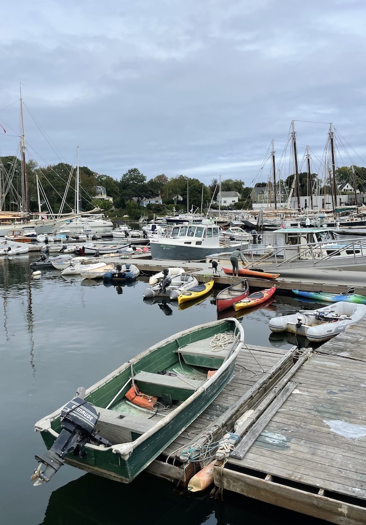 Calm harbor filled with small boats and wooden docks on cloudy day. Boat Yard, Camden Harbor, Camden, Maine, New England.