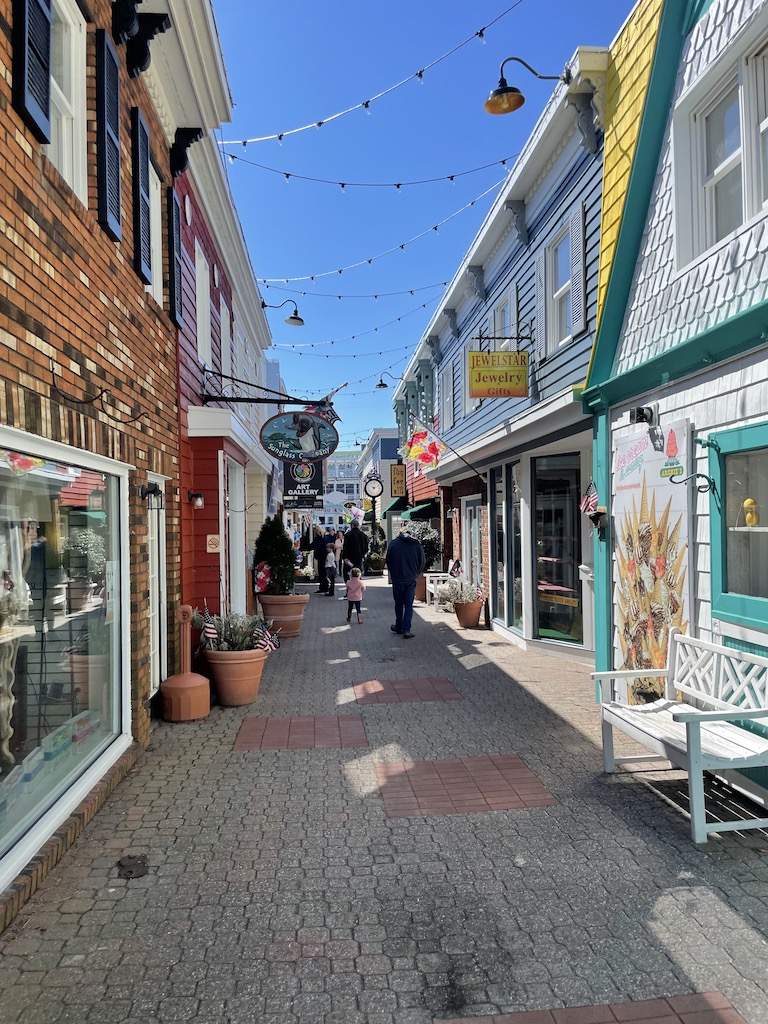 Small alley lined with cute, colorful boutique shops and string lights. Shopping in Penny Lane, Rehoboth Avenue, Rehoboth Beach, Delaware.